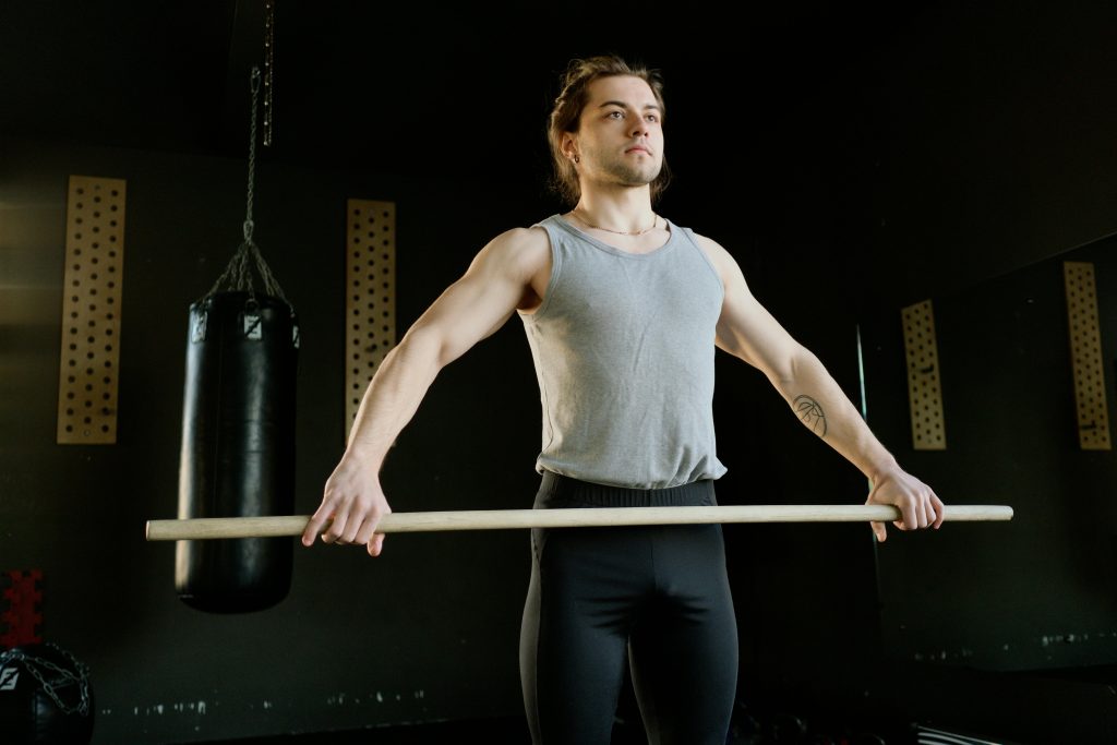 Athletic man exercising with stick in fitness gym, enhancing strength and coordination.