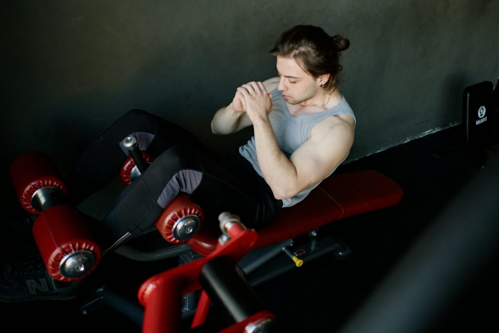 A focused man performs abdominal exercises on gym equipment, highlighting fitness and determination.