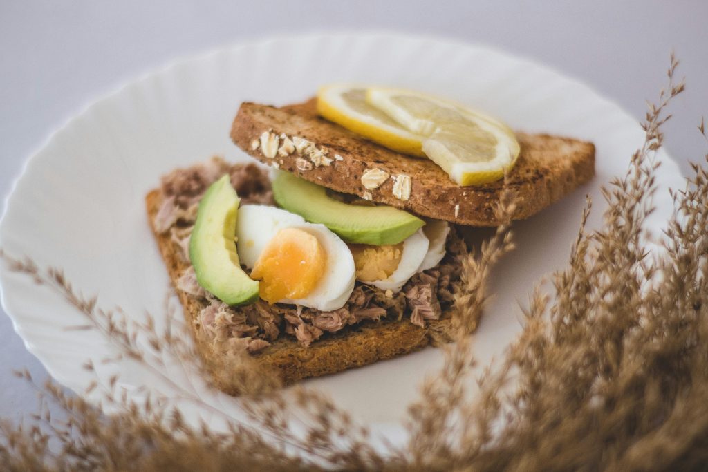 Delicious homemade tuna sandwich with avocado slices and boiled egg on wheat bread.